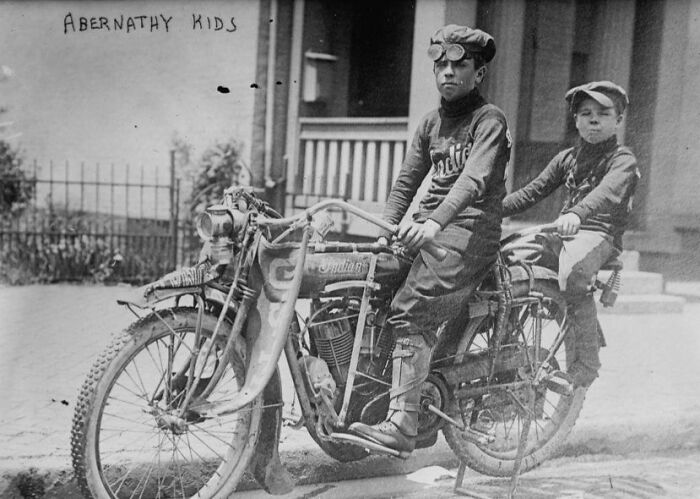 Niños en motocicleta antigua en foto histórica rara y poderosa de comunidad en línea enfocada en historia.