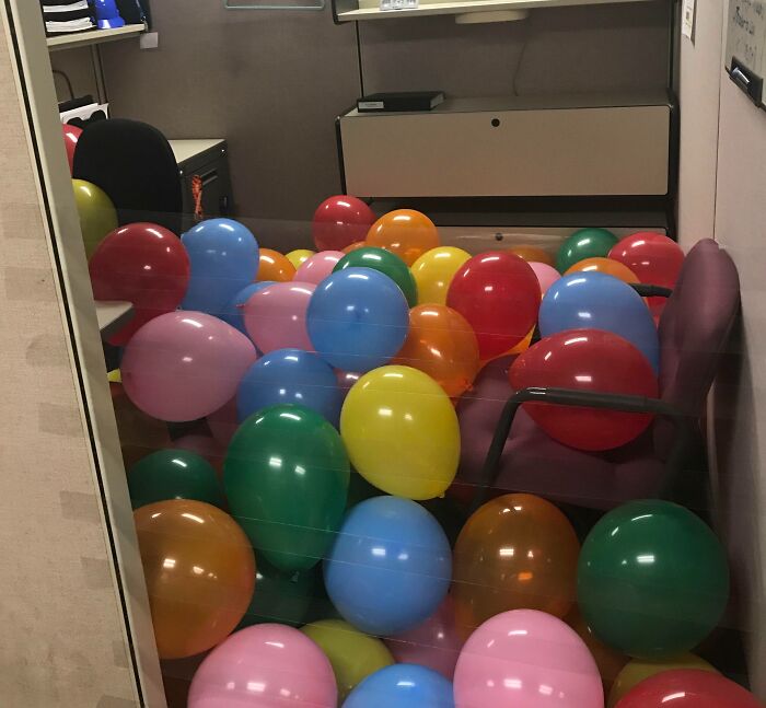 Oficina llena de globos de colores como ejemplo de venganza pequeña satisfactoria compartida online.