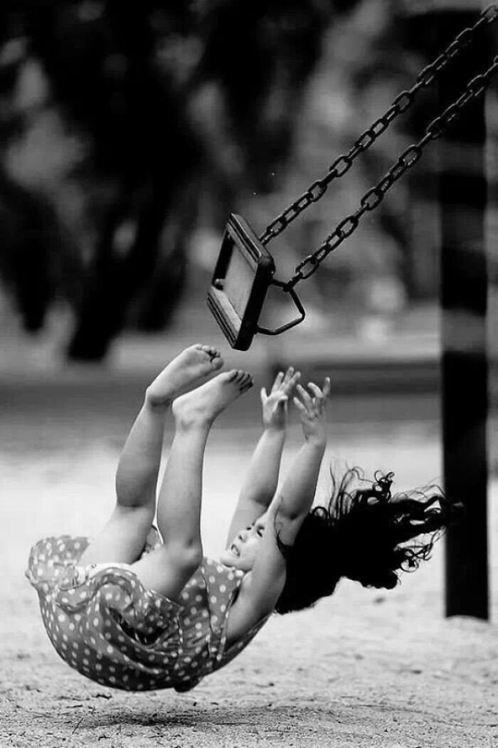 Niña cayendo de un columpio en un parque, capturada segundos antes de que algo saliera espectacularmente mal.