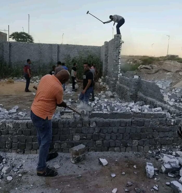 Hombres trabajando en demolición de muro mientras uno está en riesgo de accidente, momentos antes de que todo salga mal.