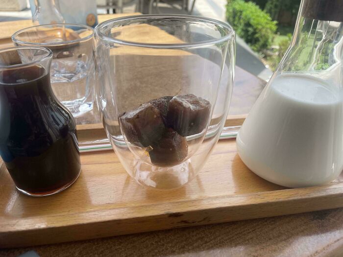 Cubitos de café congelados en vaso de vidrio con leche y café para evitar diluir la bebida, solución ingeniosa diaria.
