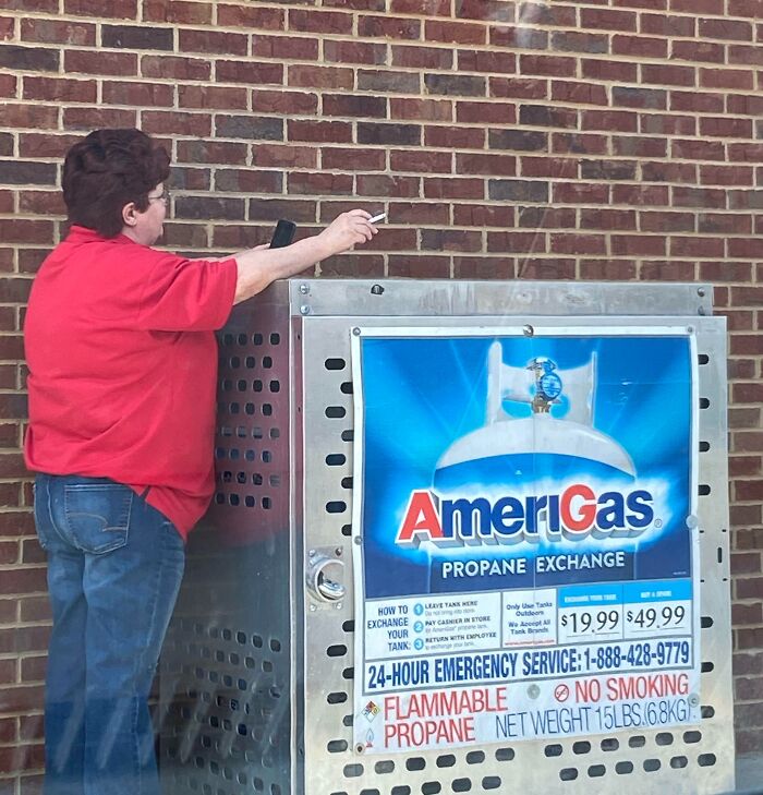 Mujer sostiene cigarrillo junto a tanque de gas propano AmeriGas, mostrando falta de sentido común y riesgo evidente.