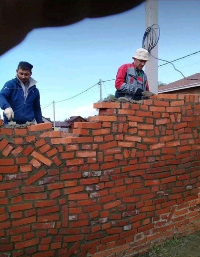 Dos albañiles construyendo un muro con un patrón de ladrillos incorrecto, un claro ejemplo de fails por seguir instrucciones al pie de la letra.