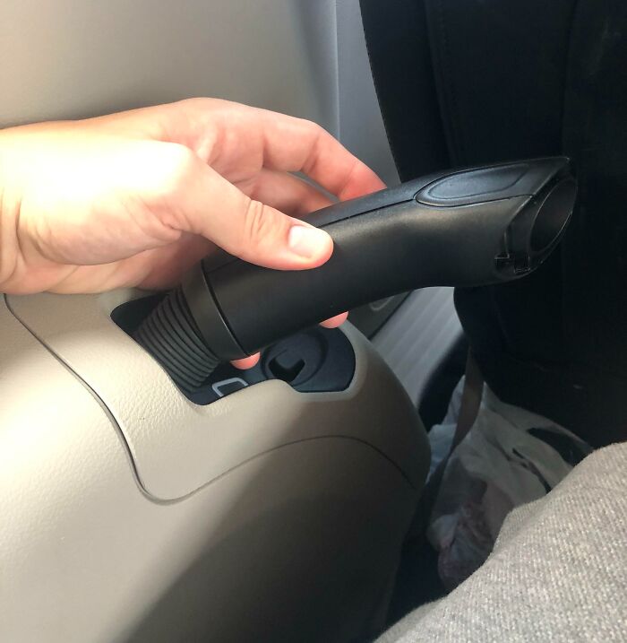 Mano usando un freno de mano modificado como solución ingeniosa para problemas cotidianos en un automóvil.