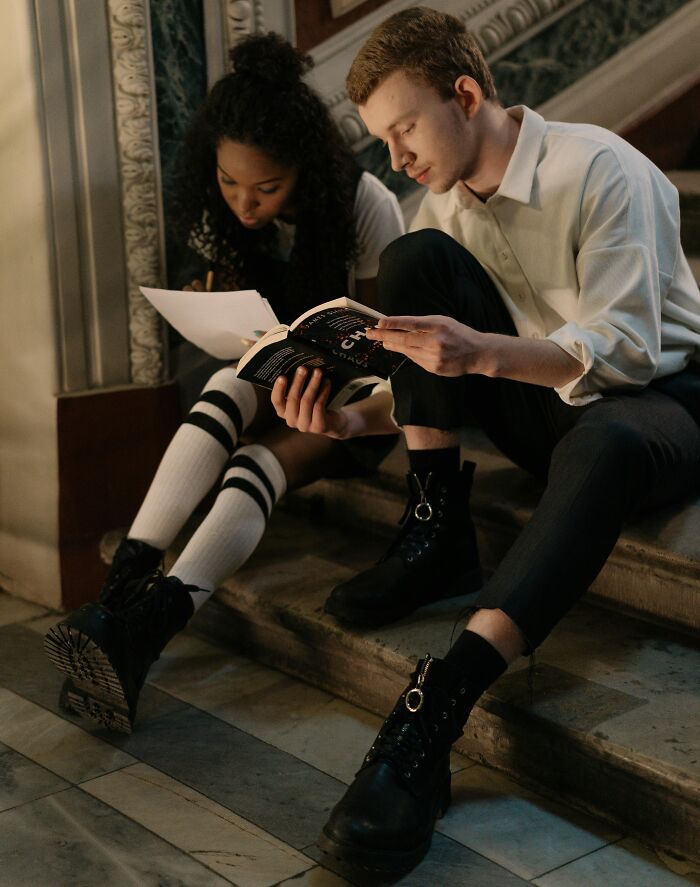 Jóvenes sentados en escaleras leyendo y escribiendo, mostrando actitudes relacionadas con vengarse de sus ex parejas.