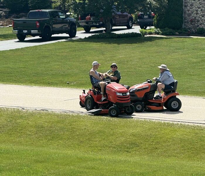 Tres hombres en cortadoras de césped rojas mostrando momentos divertidos que prueban que nunca crecieron del todo.