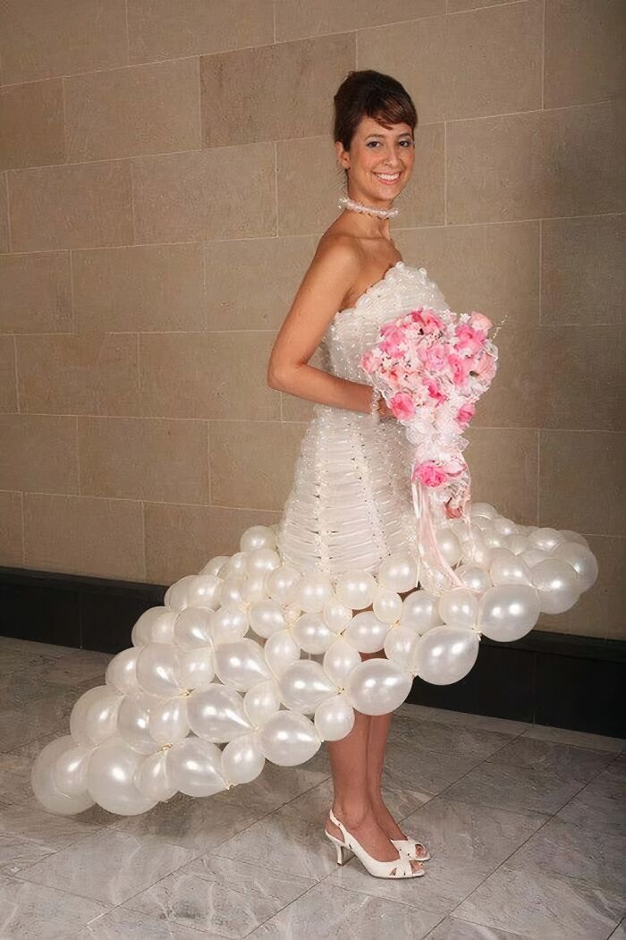 Novia con vestido de boda único hecho con globos blancos y ramo rosa, ejemplo curioso de vestidos de novia.