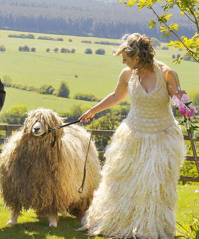 Novia con vestido de boda único sosteniendo flores mientras lleva a un animal con pelaje similar al vestido.