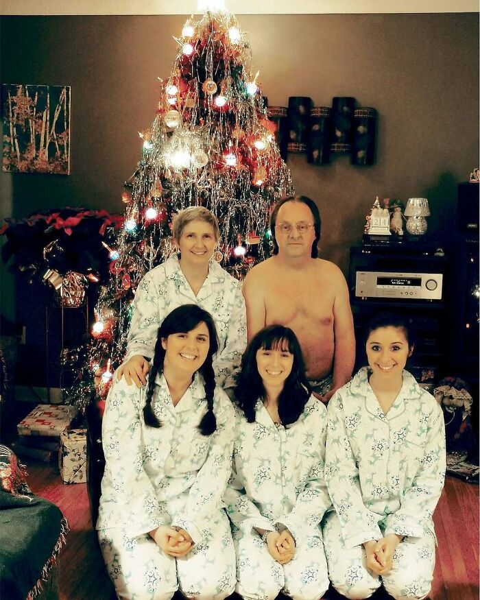 Familia en pijamas frente a árbol de Navidad, hombre sin camiseta, mostrando errores divertidos en fotos familiares.