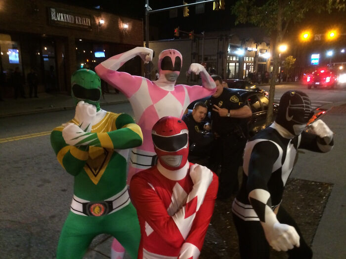 Personas disfrazadas de Power Rangers posando en la calle, en una escena divertida de fotos arruinadas con cameos inesperados.