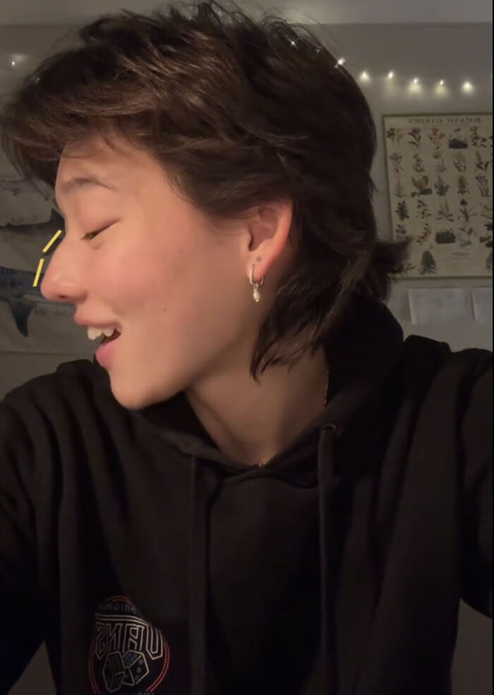 Persona sonriente con aretes celebrando lo que la hace única en ambiente íntimo y cálido.