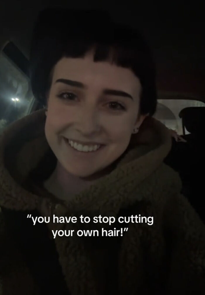 Mujer sonriente celebrando lo que la hace única con su estilo de cabello recortado en un ambiente nocturno.