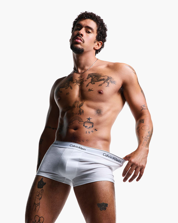 Hombre con tatuajes posando en ropa interior Calvin Klein mostrando más que una sonrisa en fotos de celebridades 2025.