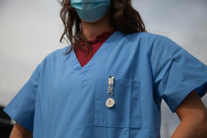 Profesional médico con mascarilla y uniforme azul en foco medio, representando experiencias que aún afectan a trabajadores médicos.