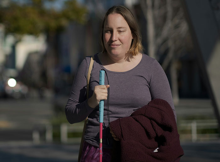 Mujer caminando con bastón y abrigo, ilustrando situaciones de señales sociales malinterpretadas y momentos incómodos legendarios.