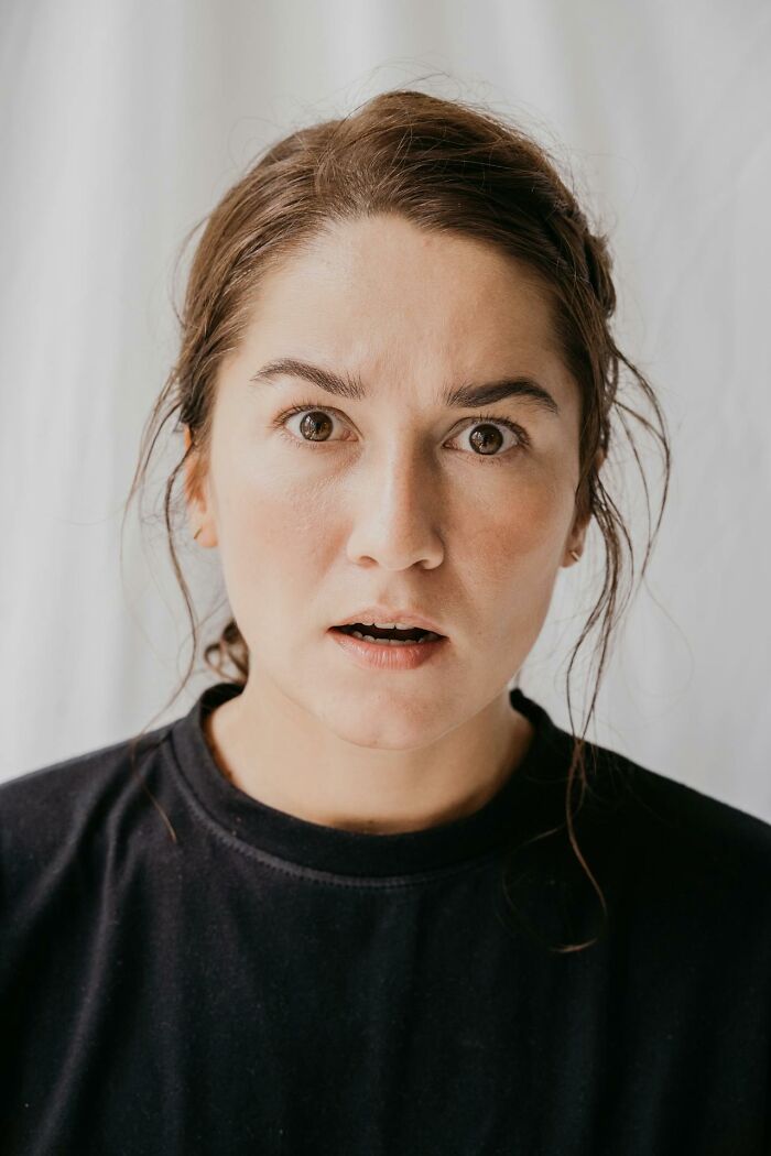 Mujer con expresión sorprendida y preocupada, reflejando momentos en que padres notan comportamientos difíciles en sus hijos.