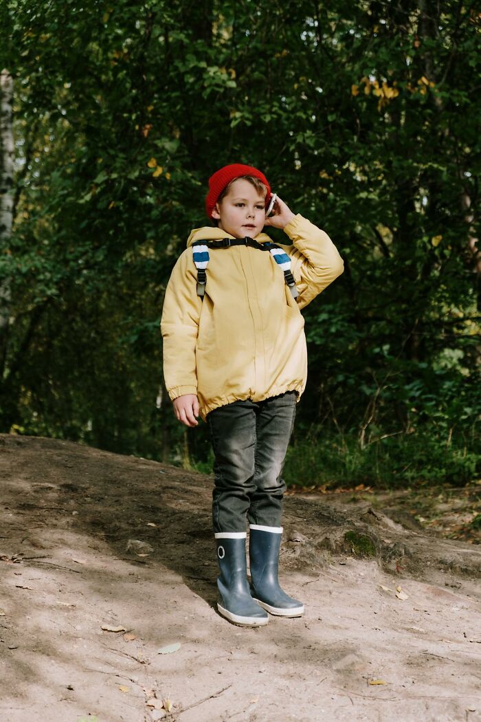 Niño con chaqueta amarilla y gorro rojo en un bosque, ilustrando momentos que llevan a pensar que los niños pueden ser malos.