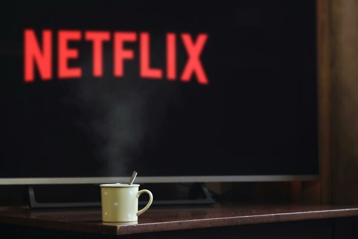 Taza con bebida caliente frente a pantalla de Netflix representando momentos para vengarse de ex parejas sin que nadie los detenga.
