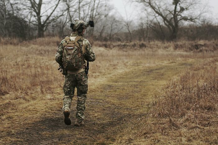 Soldado en uniforme táctico caminando por un sendero rural, ilustrando personas que decidieron vengarse de sus ex parejas.