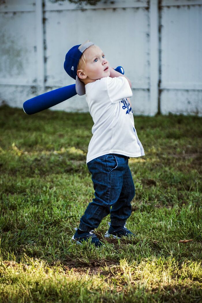 Niño pequeño con gorra y bate de béisbol, momento captado por padres que sospechan que sus hijos pueden portarse mal.