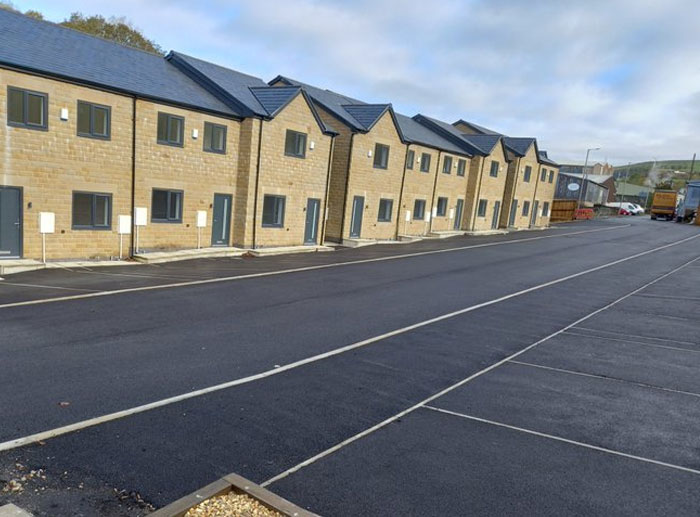 Fila de casas nuevas con diseño arquitectónico erróneo y calles mal planificadas, ejemplos de fallos de arquitectos y diseñadores.