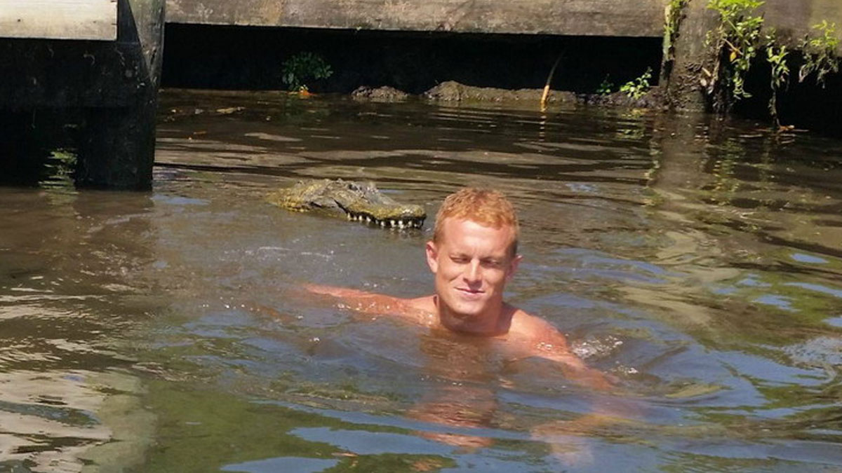 Hombre nadando cerca de un cocodrilo en agua turbia en una imagen extrau00f1a y bizarra impactante.