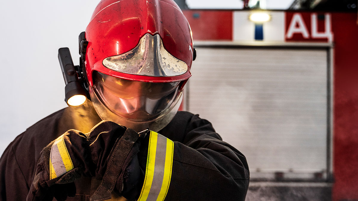 Bombero con casco rojo y guantes ajustu00e1ndose durante un rescate, mostrando impacto y situaciones de vivir mentiras.