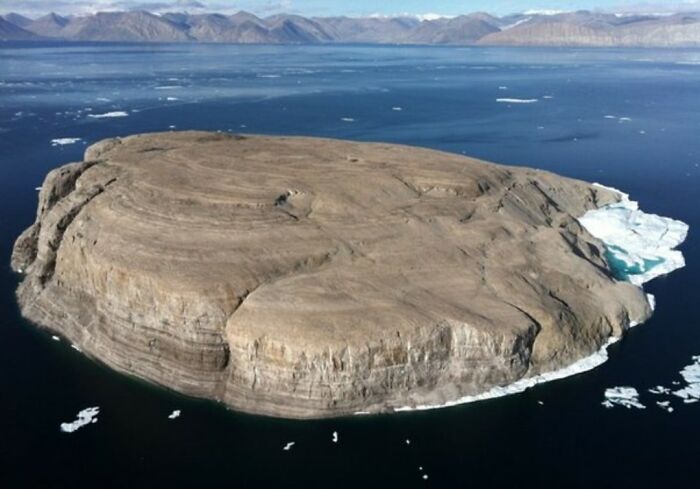 Isla en el océano rodeada de hielo flotante, representa un mundo extraño y eventos sorprendentes en la historia.