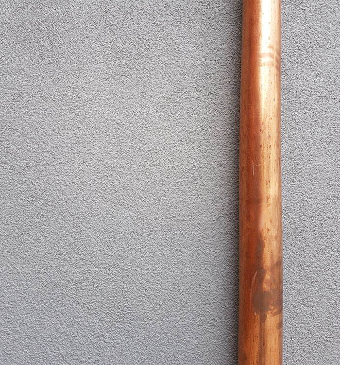 Pared gris rugosa con una tubería de cobre oxidada, simbolizando escándalos laborales que impactaron oficinas.