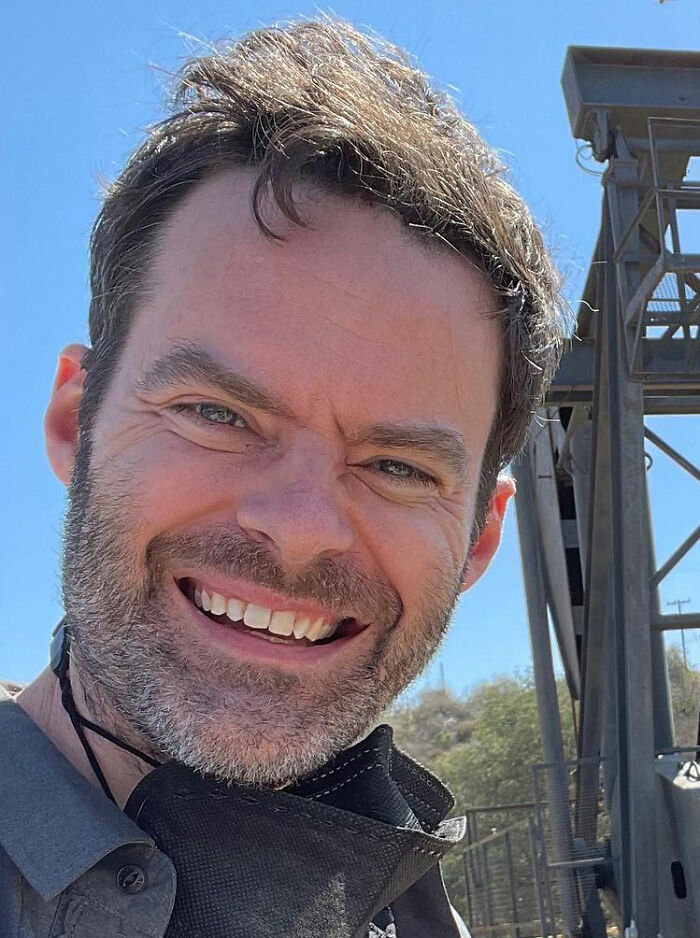 Primer plano de Bill Hader sonriendo al aire libre, relacionado con el enfrentamiento con el hijo de Rob Reiner antes de la tragedia.
