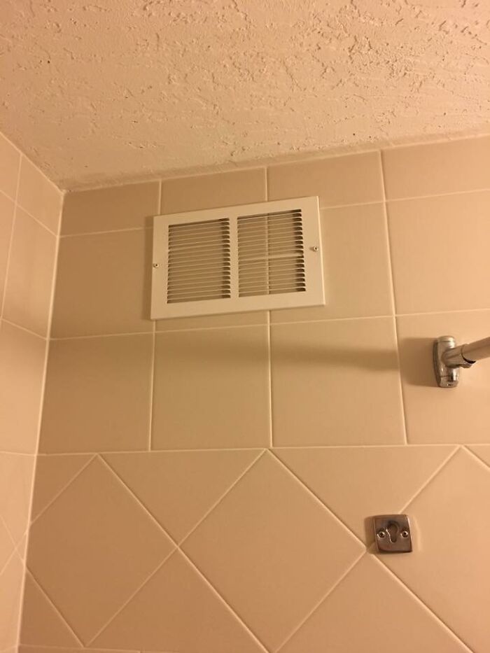 Rejilla de ventilación en baño con azulejos beige, ejemplo de cosas inútiles que resultan graciosas sin razón.