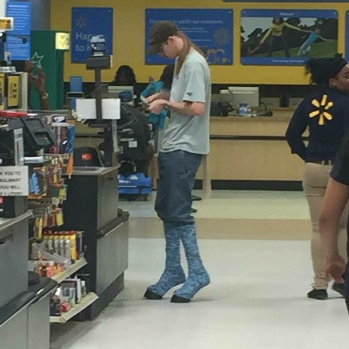 Joven con botas altas azules y camiseta gris en caja de Walmart, imagen curiosa que la gente tuvo que capturar.