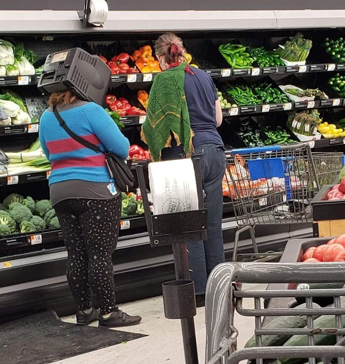 Cliente con caja en la cabeza en la sección de verduras de Walmart, mostrando una situación inusual en la tienda.