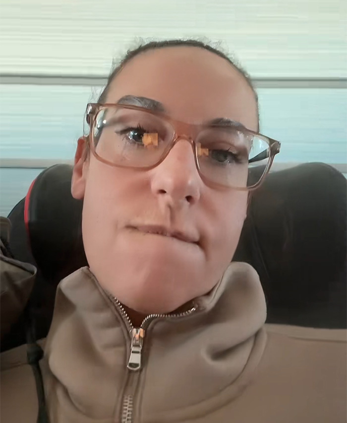 Mujer con gafas y chaqueta beige mostrando frustración por comida caducada en vuelo de Air Canada. Mujer con gafas y chaqueta beige mostrando frustración por comida caducada en vuelo de Air Canada.