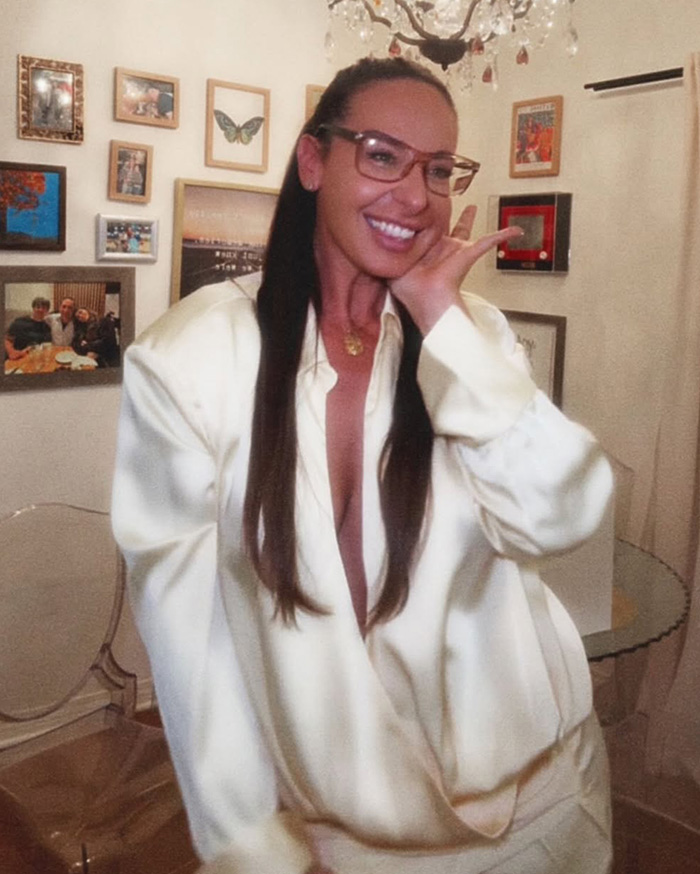 Mujer sonriente con gafas y atuendo blanco, pasajera de Air Canada en controversia por comida caducada en vuelo. Mujer sonriente con gafas y atuendo blanco, pasajera de Air Canada en controversia por comida caducada en vuelo.