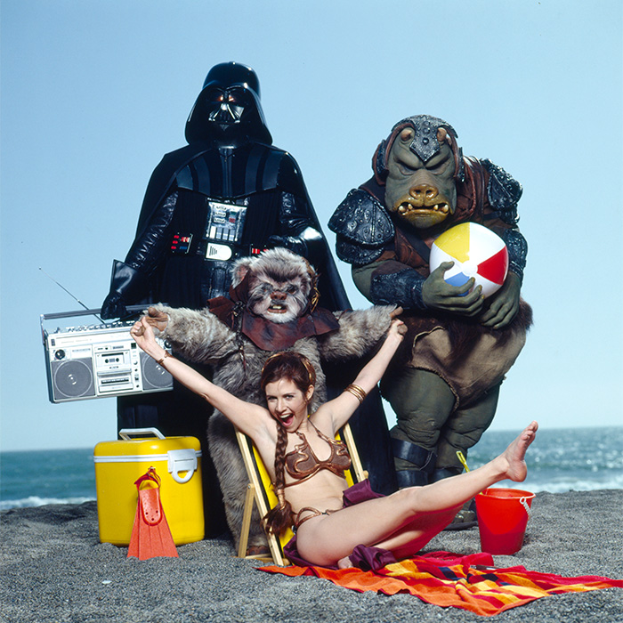 Figuras de cultura pop en la playa con personajes icónicos y disfraces llamativos en una escena divertida y única.