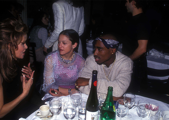 Tupac Shakur y Madonna en una mesa durante una reunión social en una foto impactante de la cultura pop inédita.