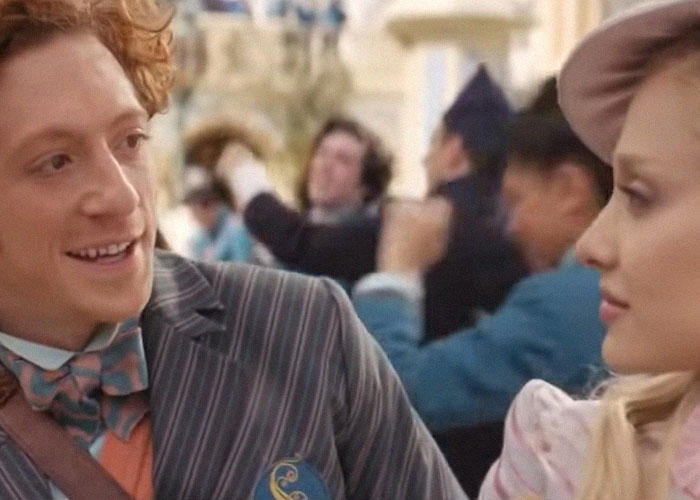 Hombre y mujer en vestimenta antigua en escena de traición notable en Hollywood, mostrando emociones complejas en evento social.