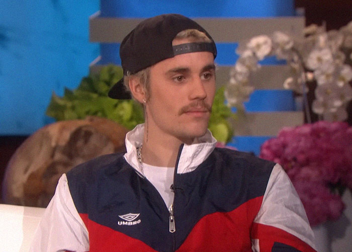 Hombre joven con gorra negra y chaqueta deportiva sentado en entrevista, ilustrando momentos de traición en Hollywood.