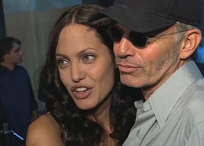 Angelina Jolie con cabello suelto junto a un hombre con gorra y gafas oscuras, momentos de traición en Hollywood.