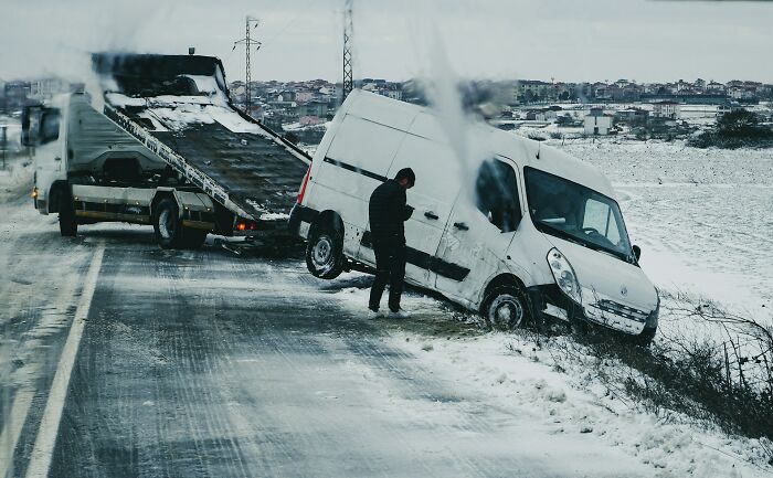 Coche blanco fuera de la carretera en nieve siendo remolcado, ejemplo de manifestaciones satisfactorias de karma instantáneo.