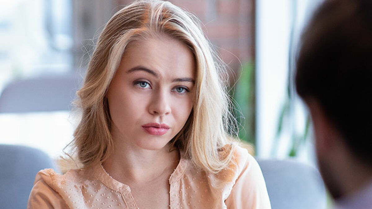 Mujer millennial con expresiu00f3n seria, en conversaciu00f3n con otra persona, representando tema de mujeres groseras.