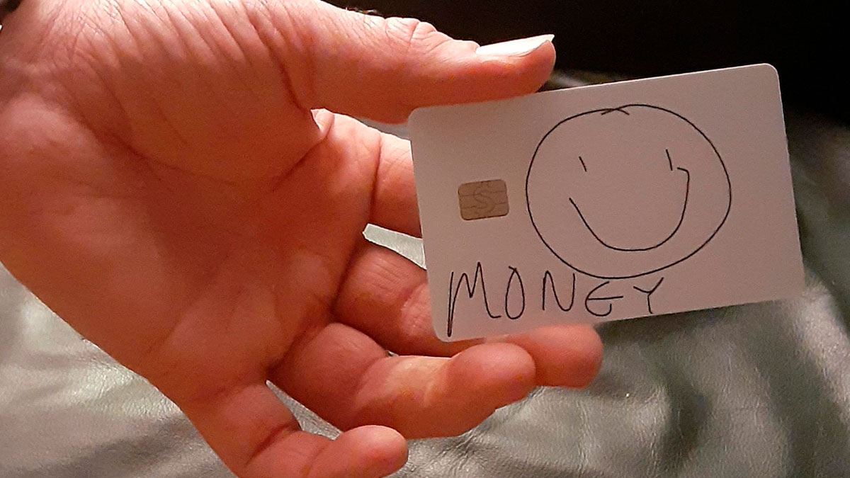 Mano sosteniendo tarjeta con dibujo infantil y texto money resaltando momentos divertidos de hombres inmaduros.
