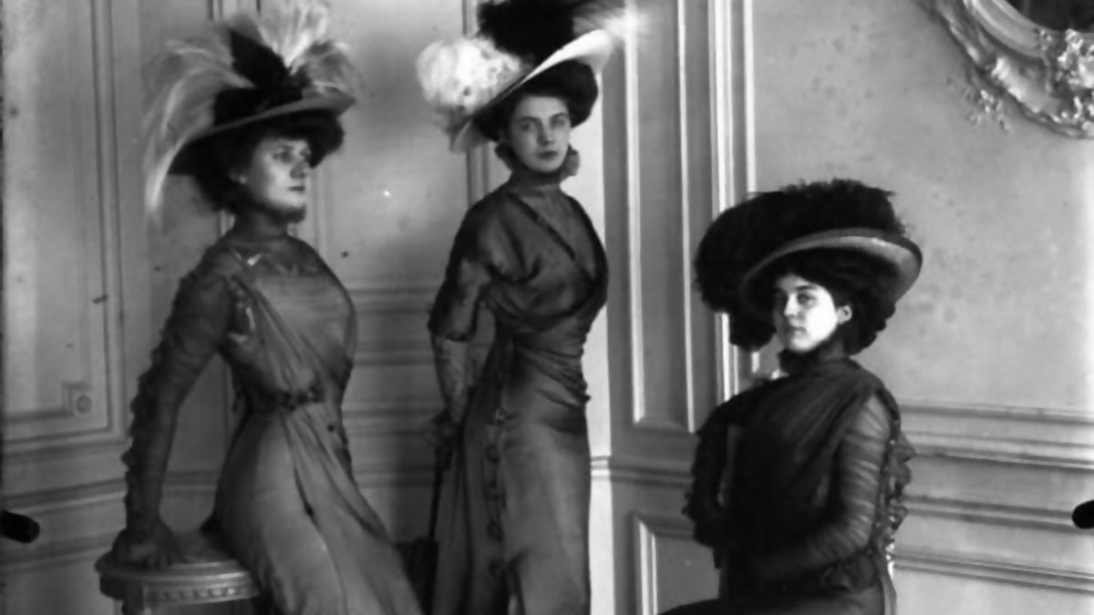 Tres mujeres con vestidos y sombreros antiguos posan en una foto histu00f3rica mostrando moda que nunca veremos en la vida real.