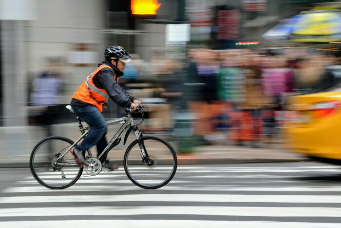 Hombre en bicicleta cruzando rápido un paso peatonal mostrando manifestaciones de karma instantáneo satisfactorias.