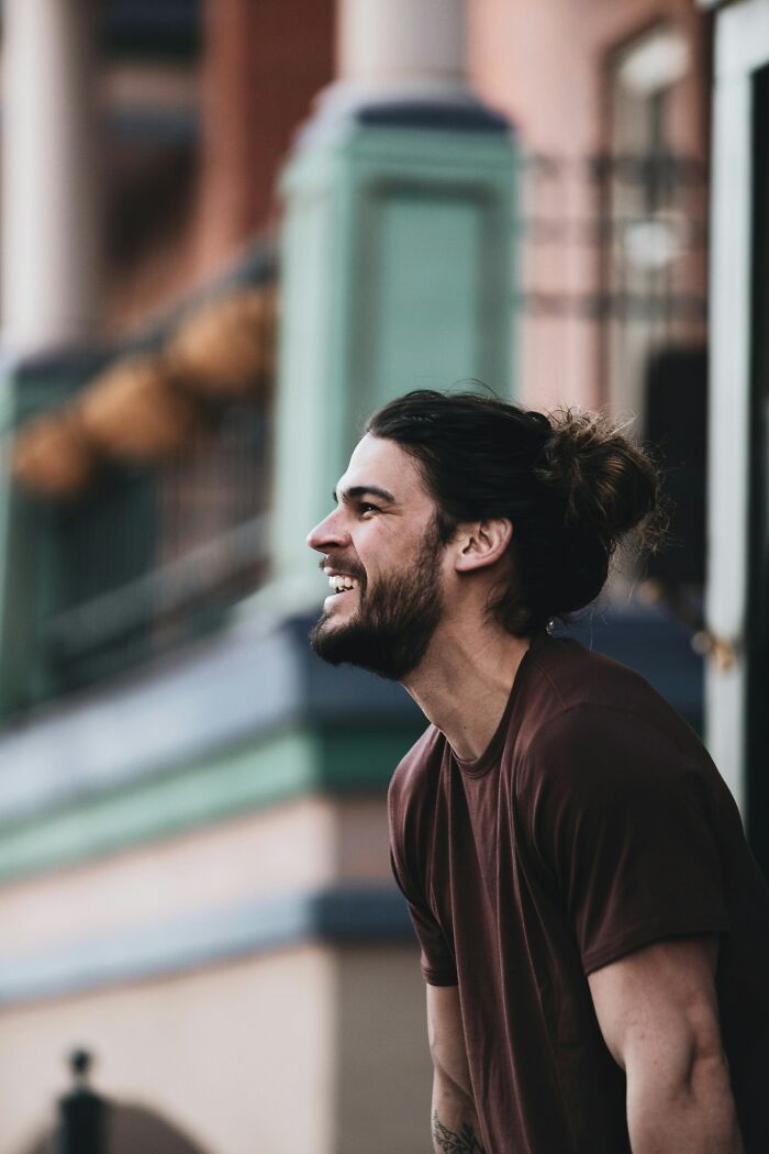 Hombre joven sonriendo con expresión ingeniosa mostrando cosas divertidas y astutas dichas en el calor del momento.