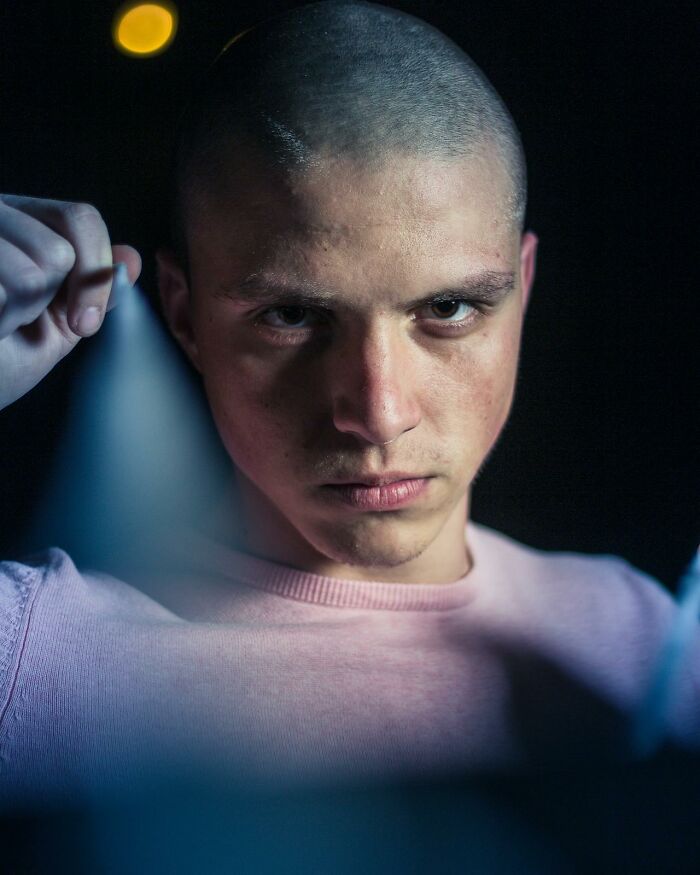 Joven con mirada intensa usando linterna en un entorno oscuro, mostrando momentazos ingeniosos y divertidos en calor del momento.