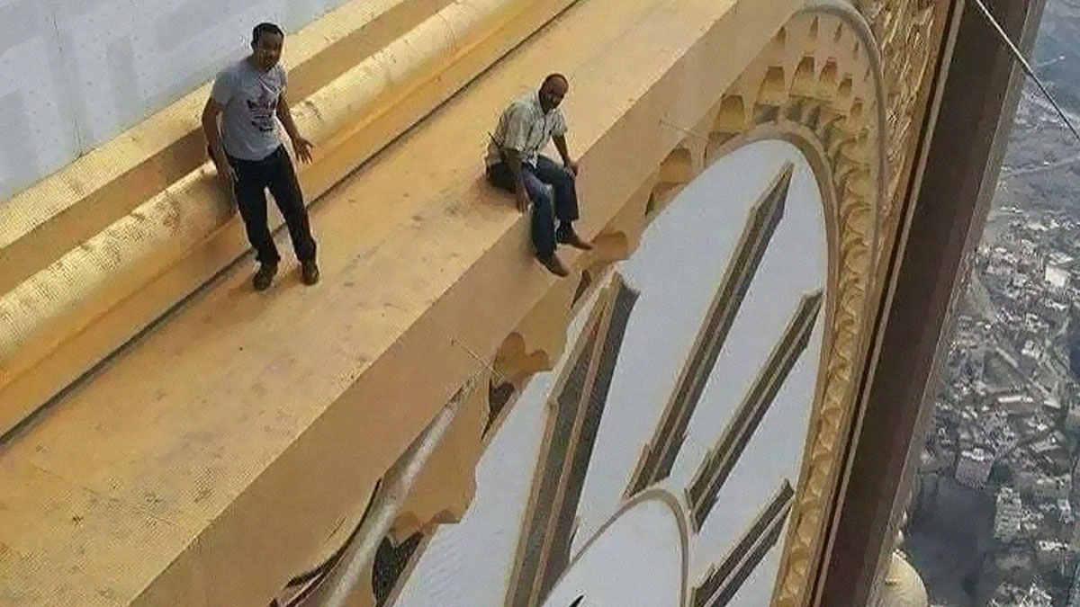 Dos hombres en un borde alto junto a un reloj gigante, mostrando una de las cosas interesantes que la gente descubriu00f3.