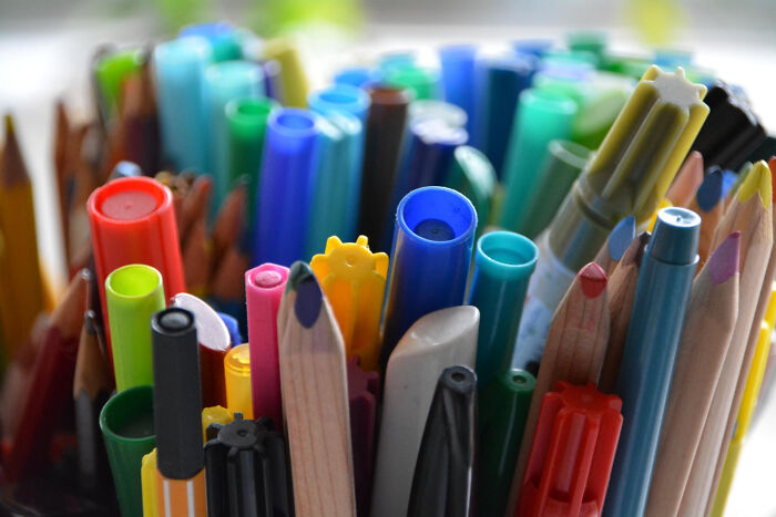 Marcadores y lápices de colores variados en soporte iluminados, representando momentos de dejar problemas y seguir adelante.