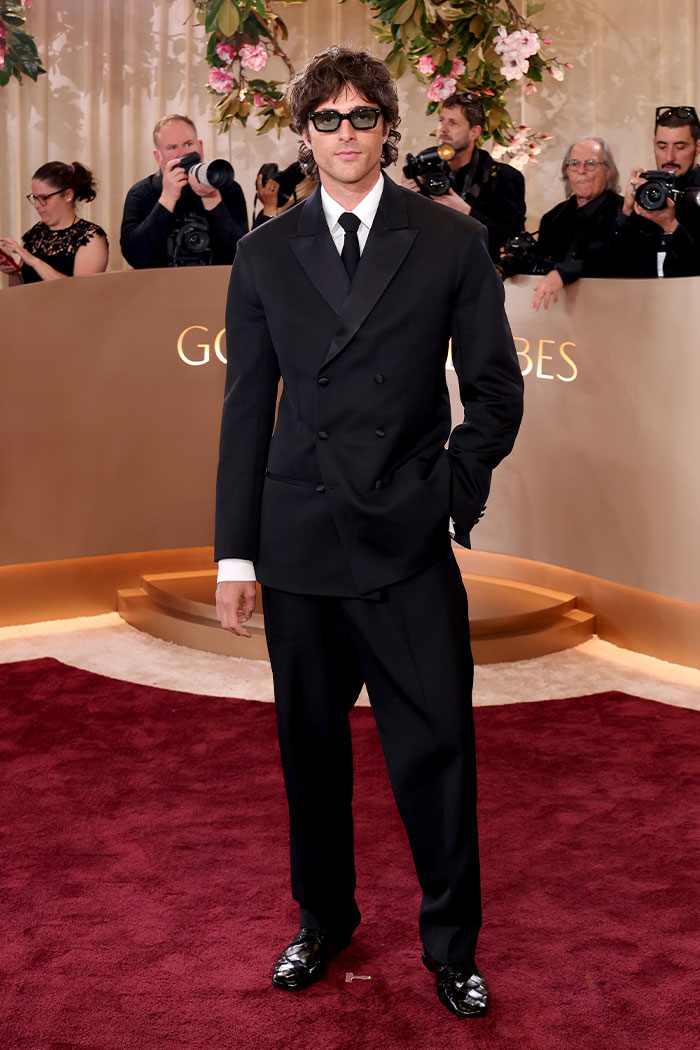 Hombre con traje negro y gafas oscuras en la alfombra roja mostrando uno de los mejores outfits de los Golden Globes.